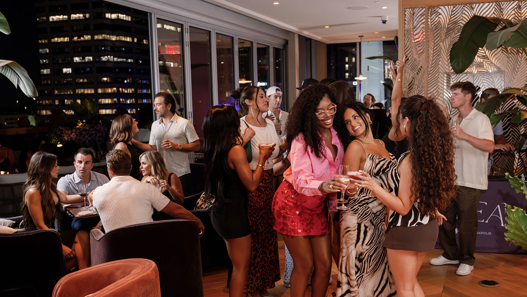 Guests toasting cocktails at Astrea rooftop